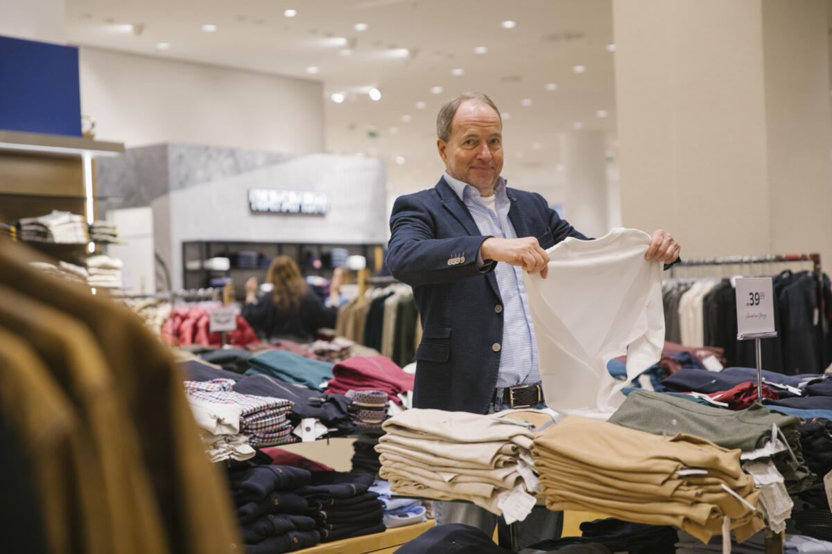 Bernhard Kloucek in einem P&C betrachtet ein weißes Shirt