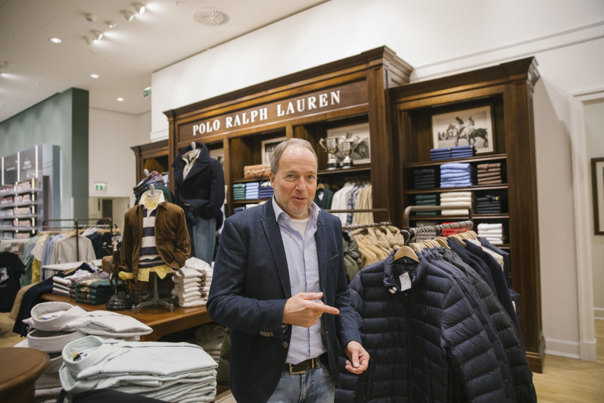 Bernhard in einem Bekleidungsgeschäft schaut sich eine Daunenjacke an