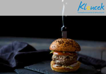 Faszinationsgen - schmackhafter Burger, in den ein Messer gerammt wurde auf dunklem Hintergrund